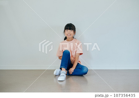 膝を立てて座る小学生の女の子 107356435