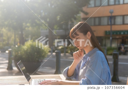 ノマドワーカー　カフェで仕事をする若い女性 107356604