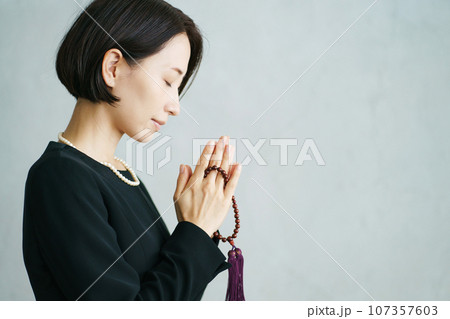 葬儀で手を合わせる女性の横顔写真 葬儀で手を合わせる女性の横顔写真 107357603