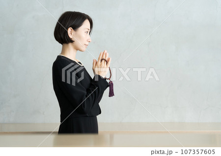 葬儀で手を合わせる女性の横顔写真 107357605