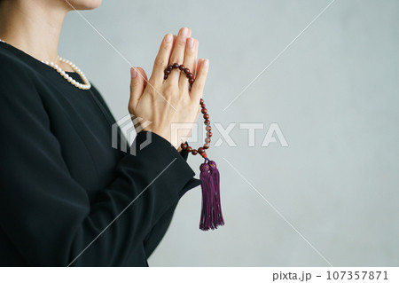 葬儀で手を合わせる女性の横顔写真 107357871
