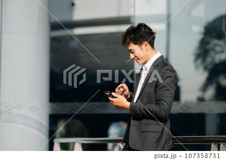 Young Asian business man working at outside business center with laptop, tablet, smartphone  and taking notes on the paper. 107358731
