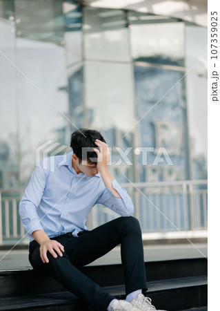 Frustrated young Asian businessman working on a laptop computer sitting at his working place in outside office 107359025