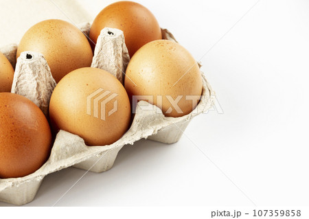 A tray of brown fresh hens eggs on white background. Eco-friendly egg production.  107359858