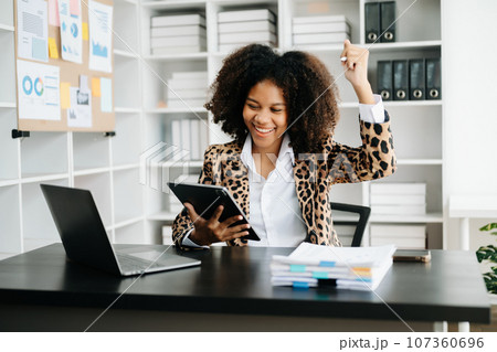 African business woman are delighted and happy with the work they do on their tablet, laptop and taking notes at the office. African business woman are delighted and happy with the work they do on their tablet, laptop and taking notes at the office. 107360696