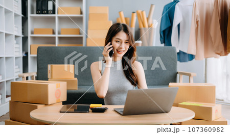 Startup small business SME, Entrepreneur owner woman using smartphone or tablet taking receive and checking online purchase shopping order to preparing pack product box. . Startup small business SME, Entrepreneur owner woman using smartphone or tablet taking receive and checking online purchase shopping order to preparing pack product box. . 107360982