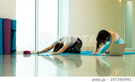 Two Asian female trainer trainee practise yoga pose Extended Puppy 107360991