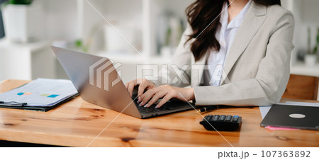businesswoman or accountant hand typing laptop working to calculate on desk about cost at home office... 107363892