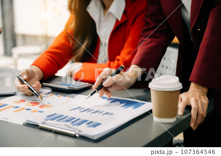 Businesswoman and team analyzing financial statement Finance task. with smart phone and laptop and  tablet. Wealth management concept in office 107364546