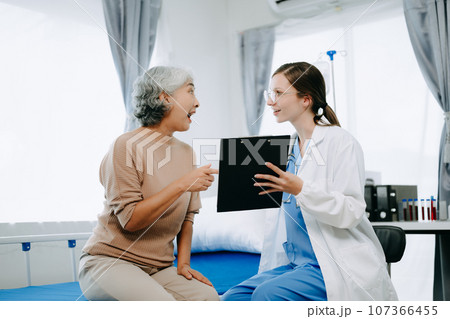 Caucasian doctor smiling take care of a young patient in hospital. Friendly nurse or therapeutic treat client Professional medical service concept. Caucasian doctor smiling take care of a young patient in hospital. Friendly nurse or therapeutic treat client Professional medical service concept. 107366455