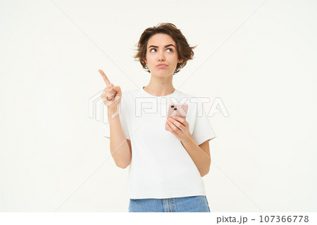Portrait of woman thinking, using smartphone and looking thoughtful, making choice, deciding, standing isolated over white background Portrait of woman thinking, using smartphone and looking thoughtful, making choice, deciding, standing isolated over white background 107366778