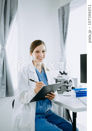 Caucasian smiling doctor or consultant sitting at a desk his neck biochemical samples, science chemical laboratory Caucasian smiling doctor or consultant sitting at a desk his neck biochemical samples, science chemical laboratory 107366851
