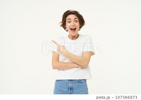 Image of excited woman, pointing finger left, showing advertisement, demonstrating brand banner, standing over white background 107366873