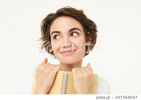 Portrait of happy woman with planner, holding notebook, reading notes and smiling, standing over white background 107368087
