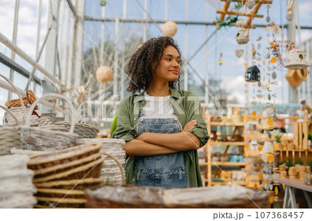 Smiling female garden shop seller standing on flower store background. Gardening concept 107368457