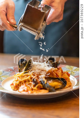 ペスカトーレパスタに粉チーズをかける ペスカトーレパスタに粉チーズをかける 107369229