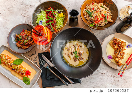 A set of Thai cuisine dishes on a table in a restaurant with a cocktail. A set of Thai cuisine dishes on a table in a restaurant with a cocktail. 107369587