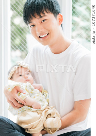 赤ちゃんを抱く新米パパ 107371640