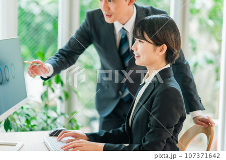 モニターを見ながら説明を受ける若いビジネスウーマン モニターを見ながら説明を受ける若いビジネスウーマン 107371642