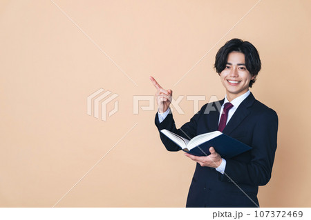 本を持って説明するスーツを着た若い男性　ビジネスマン 107372469