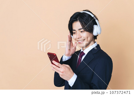 ヘッドホンとスマホで音楽を聴く男性 ヘッドホンとスマホで音楽を聴く男性 107372471