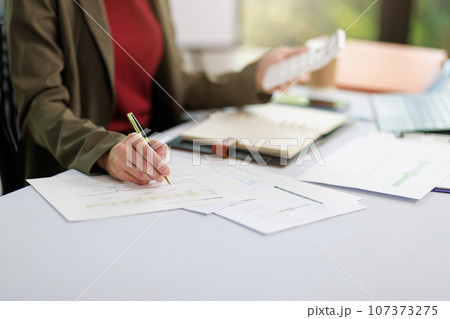Concept of business office woman working,Businesswoman smile while working about her invesment plan with analyzing document and business investment graph data by using laptop on desk in workstation. Concept of business office woman working,Businesswoman smile while working about her invesment plan with analyzing document and business investment graph data by using laptop on desk in workstation. 107373275