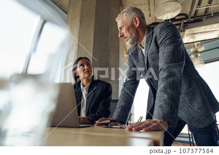 Senior male boss discussing online project with employee showing presentation to team leader 107377584