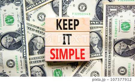 Keep it simple symbol. Concept word Keep it simple on beautiful wooden block. Dollar bills. Beautiful dollar bills background. Business motivational keep it simple concept. Copy space. 107377912