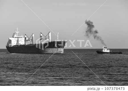 Bulk carrier and tug boat sail the Black Sea. Varna harbor 107378473