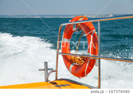 Red lifebuoy is on railings of fast motor boat Red lifebuoy is on railings of fast motor boat 107378480