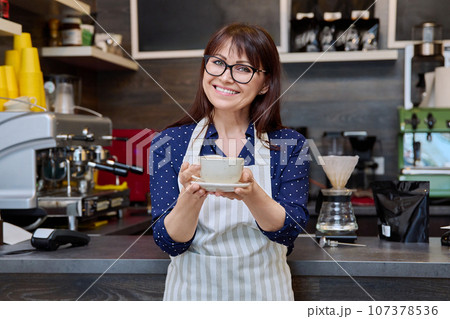 Portrait of female small business owner wearing apron near coffee shop counter Portrait of female small business owner wearing apron near coffee shop counter 107378536