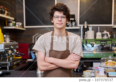 Young confident male coffee shop worker with crossed arms Young confident male coffee shop worker with crossed arms 107378537
