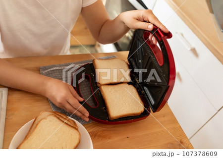 women's hands make toast in a toaster 107378609