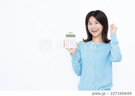 白い背景の前で電卓を持ちガッツポーズをしている30代の女性 白い背景の前で電卓を持ちガッツポーズをしている30代の女性 107380699