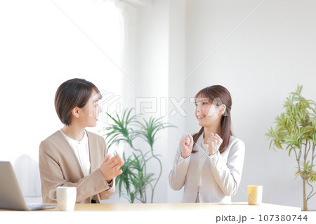 ワンオンワン_部下の仕事ぶりを褒める女性管理職と喜ぶ部下_1 107380744