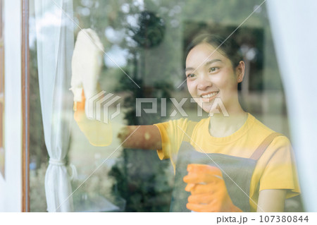 Woman doing household chores and wiping windows in the house on weekends Woman doing household chores and wiping windows in the house on weekends 107380844