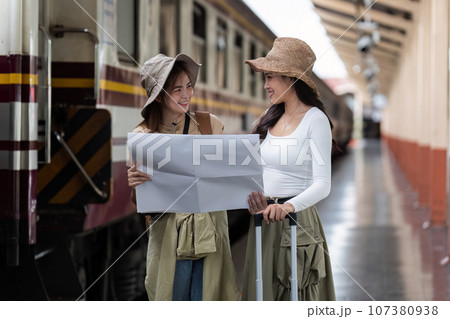 Young womans female traveler looking on map while waiting for the train at train station 107380938
