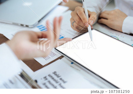 Businesswoman talks to colleague about strategy on tablet while meeting Businesswoman talks to colleague about strategy on tablet while meeting 107381250