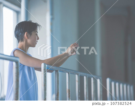 屋上でスマホを見る若い女性　スポーツ観戦　 107382524