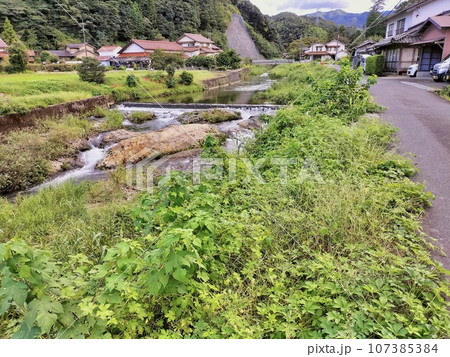 初秋の渓流に沿う農村地帯 107385384