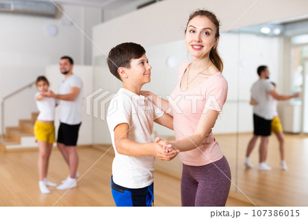Young woman dancing waltz in pair with tween son during family dance class Young woman dancing waltz in pair with tween son during family dance class 107386015