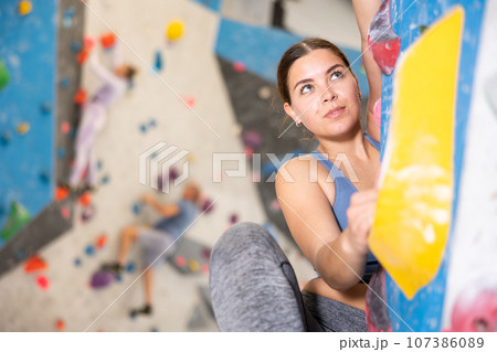 Focused sporty young girl climbing on bouldering wall 107386089