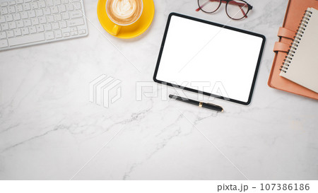 Office desk workplace with blank screen digital tablet, keyboard, eyeglass, pen, noebook and cup of coffee, Top view flat lay with copy space. Office desk workplace with blank screen digital tablet, keyboard, eyeglass, pen, noebook and cup of coffee, Top view flat lay with copy space. 107386186