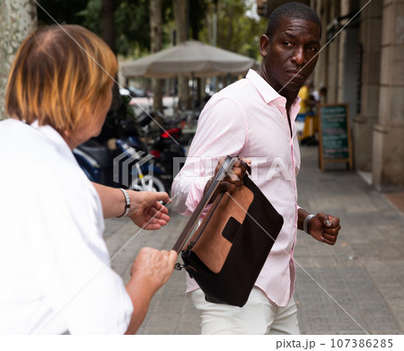 Man trying to thieve female handbag Man trying to thieve female handbag 107386285