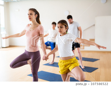 Family practicing yoga in pairs at studio 107386522