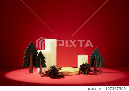 Christmas banner with blank space for presentation product. A round golden tray decorated with dried pine cones, paper plants and scented candles on a red background Christmas banner with blank space for presentation product. A round golden tray decorated with dried pine cones, paper plants and scented candles on a red background 107387500
