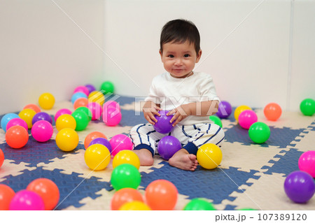 happy infant baby playing colorful balls in playpen happy infant baby playing colorful balls in playpen 107389120