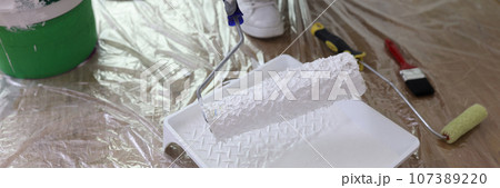 Worker holds roller brush over tray in renovated room 107389220