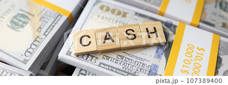 Wooden square blocks in form of word Cash on pack of dollars 107389400
