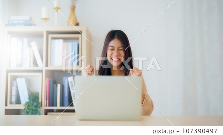 Funny euphoric young asian woman celebrating winning Funny euphoric young asian woman celebrating winning 107390497